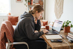 A person sitting at a desk with hunched shoulders and rounded back while working on a laptop.